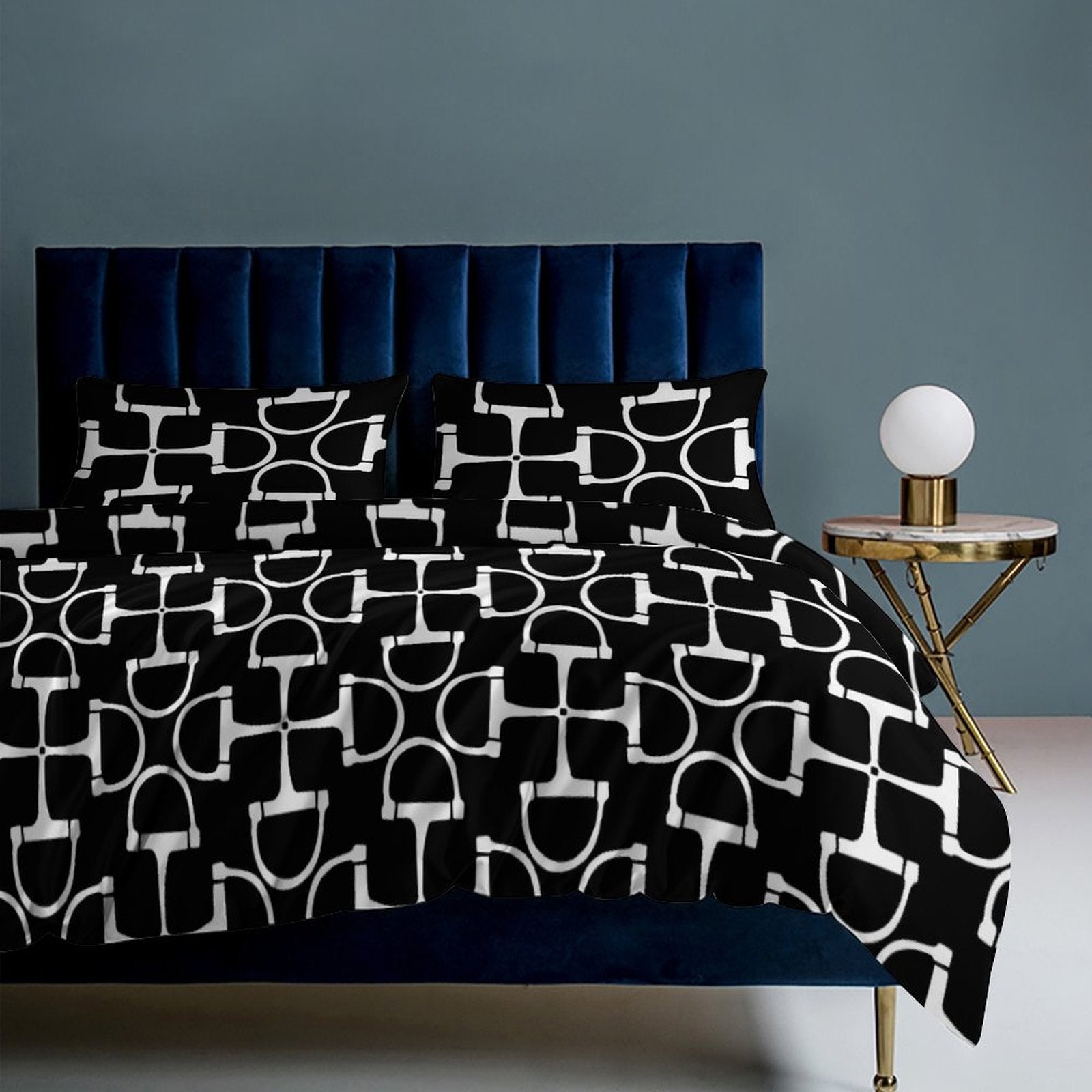 Bed with black and white patterned bedding against a gray wall.