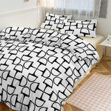 Bedding set with black and white geometric pattern on a bed in a bedroom.
