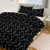 Black bedding set with white bone pattern on a bed in a bedroom.