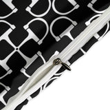 Close-up of a white strap with a metal buckle against a black and white patterned background.